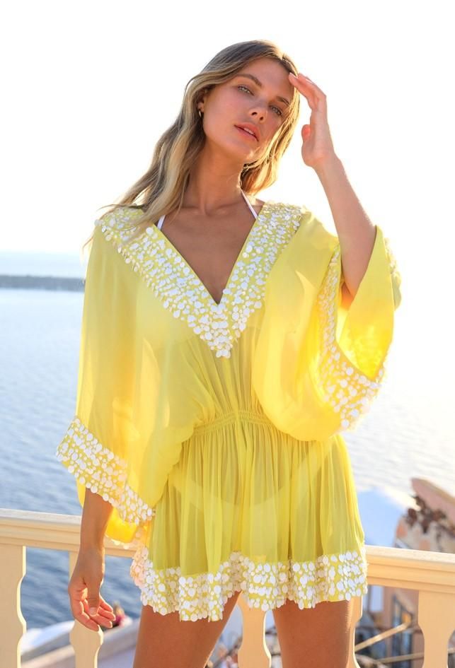 This product is a bright yellow sheer beach cover-up tunic designed with a playful.