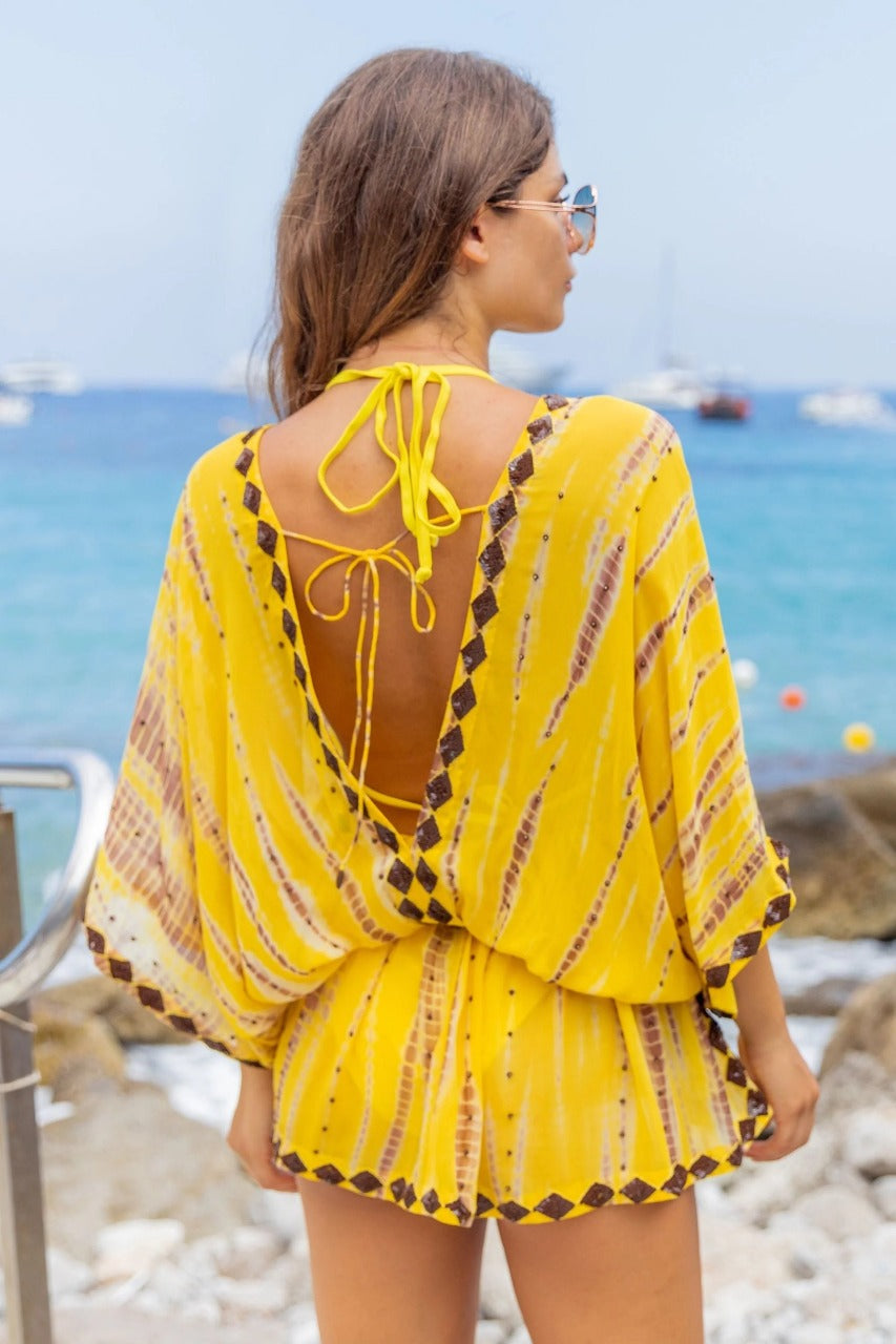 This product is a bright yellow sheer beach cover-up tunic designed with a playful.