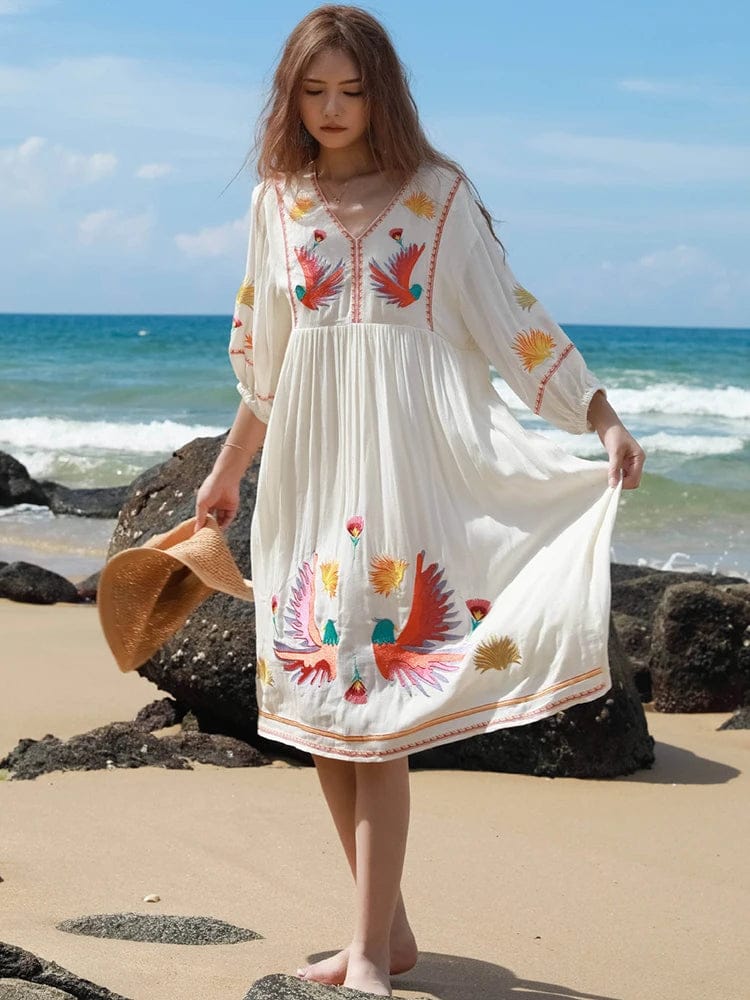bohemian-style beach dress. It is made from a flowy, lightweight fabric in an off-white or cream color, perfect for warm weather.