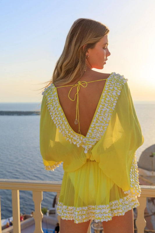 This product is a bright yellow sheer beach cover-up tunic designed with a playful.