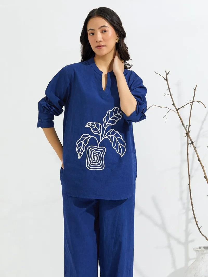 Trousers: High-waisted with a wide-leg cut, matching the fabric and color of the shirt for a cohesive look.