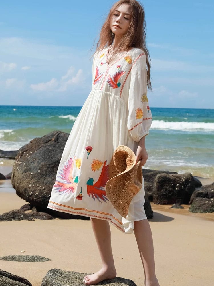 bohemian-style beach dress. It is made from a flowy, lightweight fabric in an off-white or cream color, perfect for warm weather.